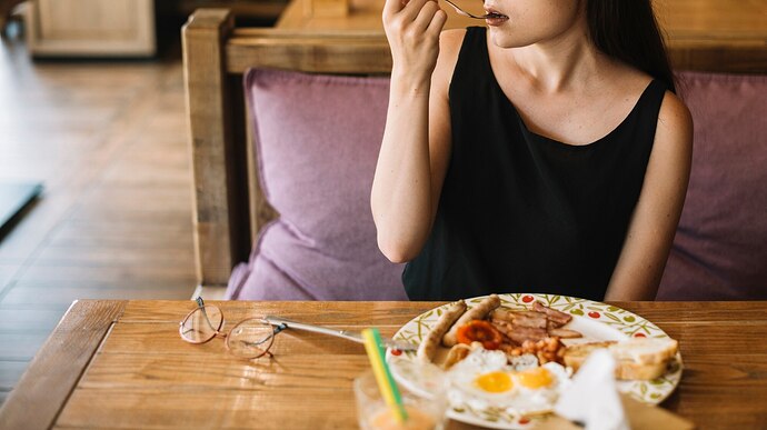 woman-eating-breakfast-restaurant_23-2147871307